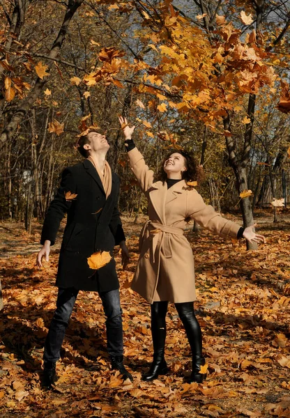 Young man in dark coat and woman in trendy beige coat