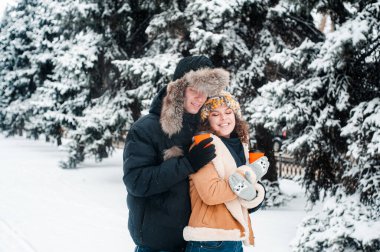 Young beautiful couple in winter forest. Happy couple has fun with snow.