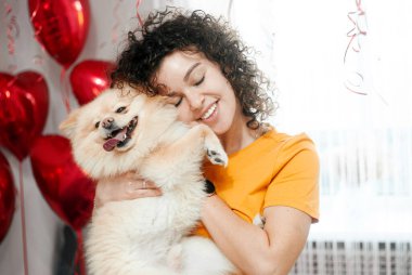 young beautiful woman with red curly hair and a golden dog on a couch at home