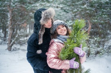 Young beautiful couple in winter forest. Happy couple has fun with snow.
