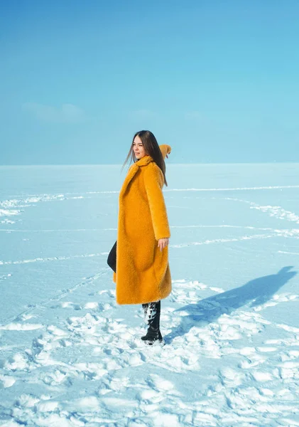 若いですランニング女性で黄色コート歩く上の雪氷 — ストック写真
