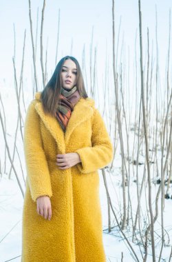 young beautiful woman in yellow coat posing outdoors