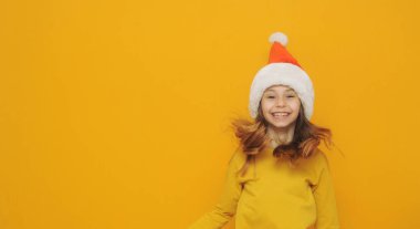 adorable little girl in santa hat on yellow background, space for text.
