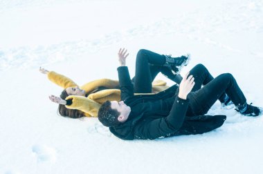 couple in love having fun and hugging on snow in the winter forest