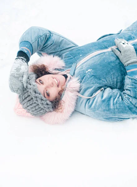 happy woman in a hat and a scarf on a snow background in a forest with a snowy landscape.