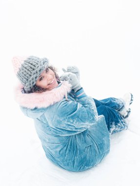 happy woman in a hat and a scarf on a snow background in a forest with a snowy landscape.