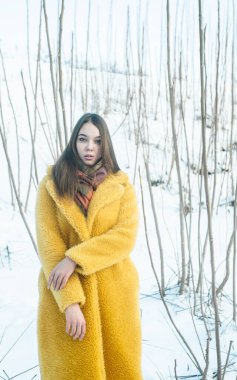 woman in yellow coat walking on snowy ice. 