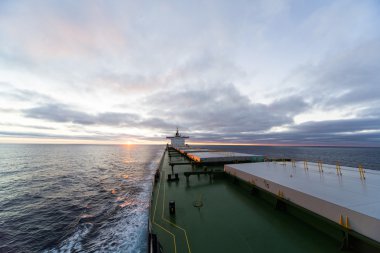 Cargo ship underway at sunset clipart