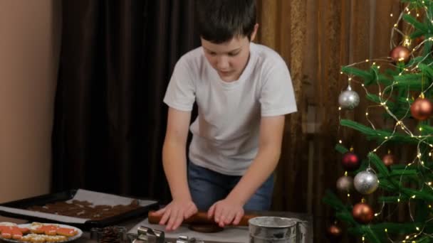 その少年はジンジャーブレッドを作る 家庭料理 自家製だ ジンジャーブレッドを調理する クラフト紙の上のジンジャーブレッドクッキー — ストック動画
