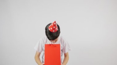 Kafasında kırmızı bir şapka ve elinde kırmızı bir torba olan küçük bir çocuk. Hediye sürpriz oldu.. 