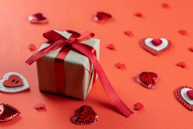 Kırmızı zemin üzerinde kırmızı kalpler olan şenlikli bir kompozisyon. Sevgililer Günü konsepti. Hediye. Boşluğu kopyala