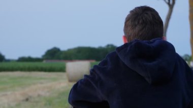 Boy's back against the background of the field with sheaves on the field.