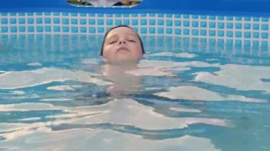The boy swims in the pool. Summer holidays in the pool
