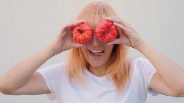 Şükran Günü. Beyaz tişörtlü, kızıl saçlı bir kız iki balkabağı tutuyor. balkabakları