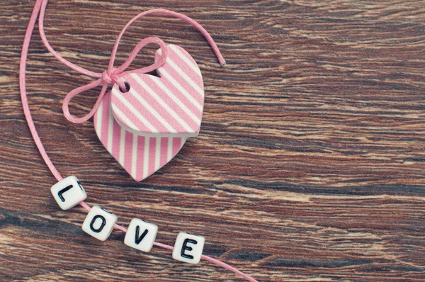 Pink hearts on wooden board with pink ribbon and letters — Stock Photo, Image