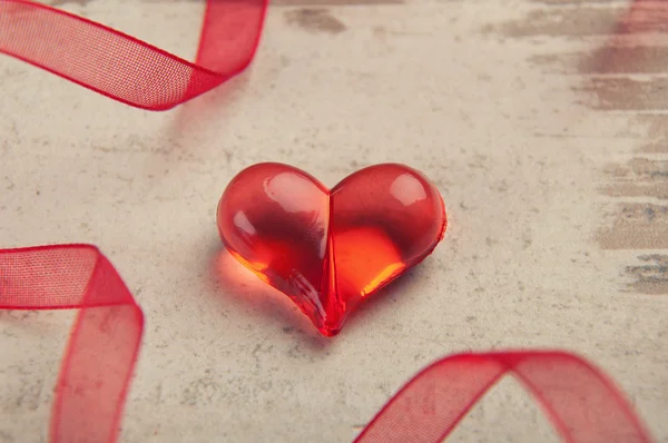 Červené srdce na dřevěné desce s červenou stužku — Stock fotografie