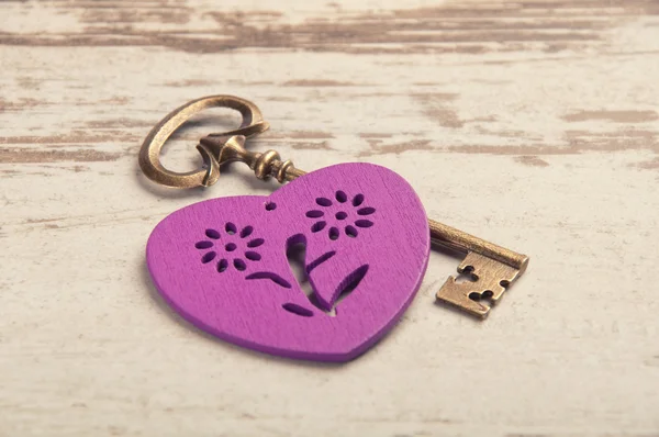 Violet wooden heart on wooden desk with key and ribbon — Stock Photo, Image