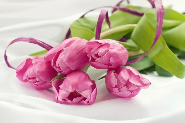 Pink tulips on white silk with ribbon — Stock Photo, Image