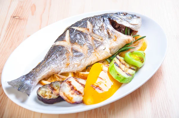 Paistettua kalaa paistettuja vihanneksia lautasella — kuvapankkivalokuva