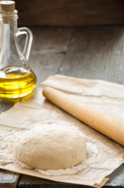 wooden rolling pin with freshly prepared dough for pizza