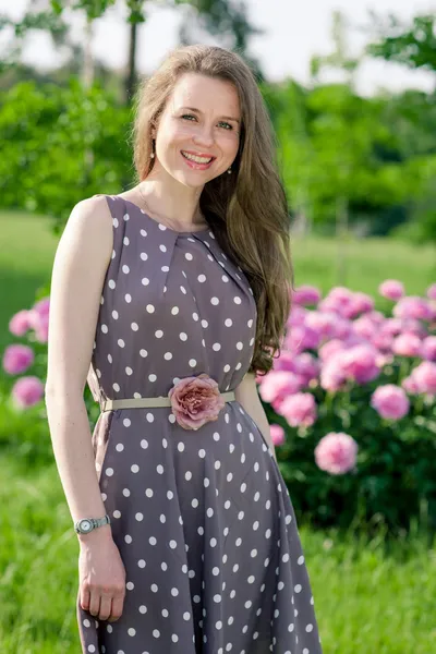 Bella giovane donna nel parco vicino peonis — Foto Stock