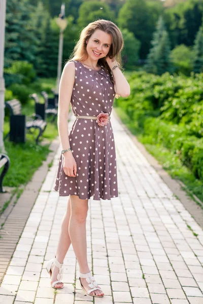 Beautiful young woman walking along the road in summer park — Stock Photo, Image