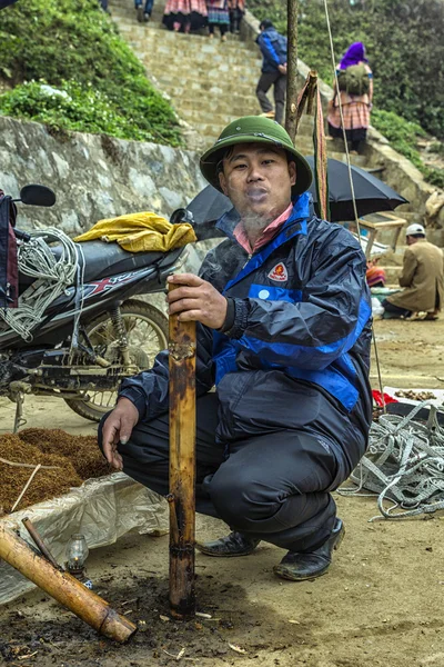 在上周日市场大管男人吸烟烟草. — 图库照片