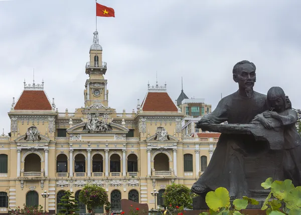 Ho chi minh standbeeld en saigon city hall met vlag. — Stockfoto