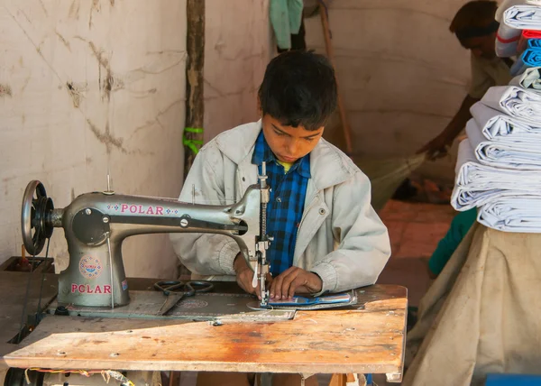 Nagaur in rajasthan india - februari 2011 - kinderarbeid: jongen naaien in stand op de markt. — Stockfoto