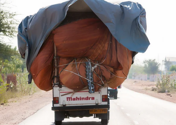 Rajasthan in india - februari 2011 - gangbare praktijk van het laden van een pick-up truck aan de max en drijven op de weg. — Stockfoto