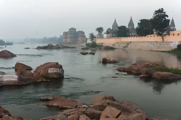Ghat i bundela cenotafami pojawiają się wczesnym rankiem nad rzeka betwa mglisty w Indiach orchha. — Zdjęcie stockowe