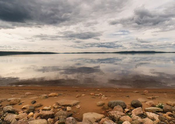 Rocky beach frentes lago que refleja cielos dramáticos en la Vuelta Finlandesa — Foto de Stock