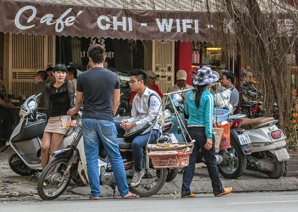 Street scene with young people chatting and food vendor in front