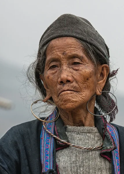 Portret van de bejaarde vrouw van de hmong tegen grijze hemelen close-up. — Stockfoto