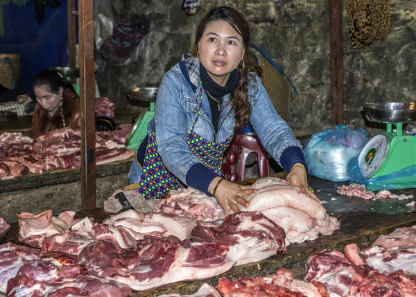 Fleischereifachverkäuferin greift nach Fettstücken von einem Tisch voller geschnittener M — Stockfoto