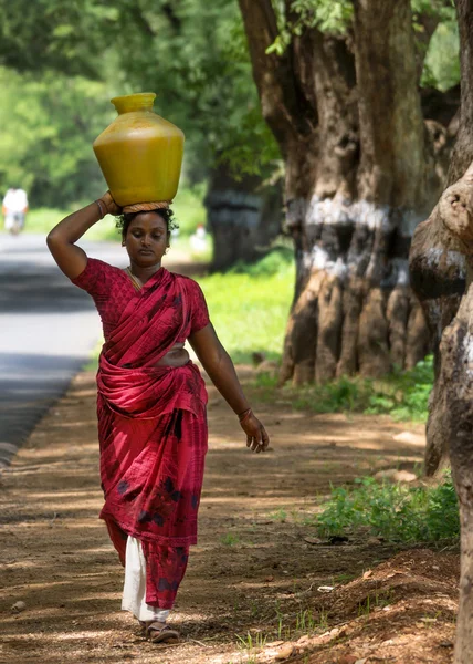 Indyjski kobieta niesie ze sobą garnek wody na głowę. — Zdjęcie stockowe