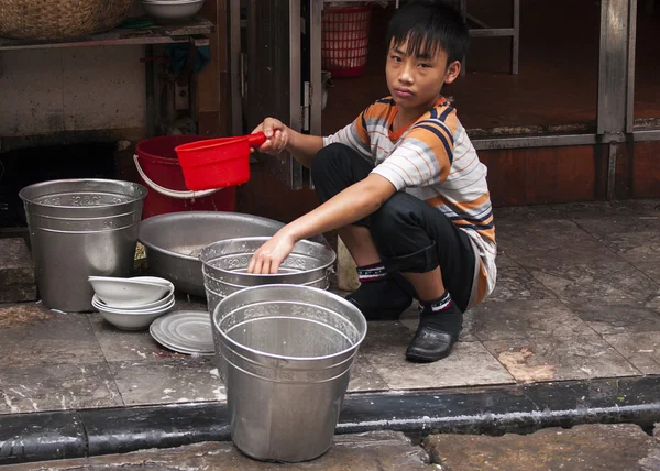 Chłopak robi naczynia na chodniku. — Zdjęcie stockowe