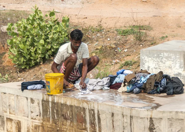 Człowiek robi pranie ręcznie na betonowej mostu na rzece. — Zdjęcie stockowe