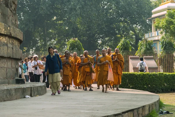 Buddhist monks, followed by pilgrims, circle the Dhamekh Stupa. — Stock Photo, Image