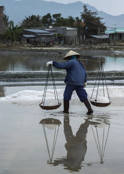 Una mujer lleva dos cestas llenas de sal recién cosechada —  Fotos de Stock
