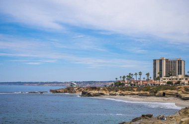 La Jolla, California, ABD - 3 Ekim 2021: Sahil şeridi boyunca Wipeout ve South Case Sahili boyunca kayalıklarda Çocuk havuz evi ve mavi bulutlar altında büyük 939 apartman dairesi.