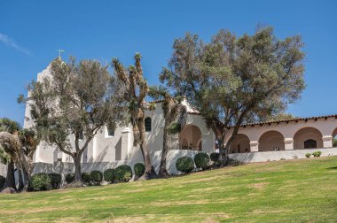 San Diego, California, ABD - 3 Ekim 2021: Junipero Serra Müzesi beyaz binası ve tepesinde mavi gökyüzü ve önde yeşil yapraklar