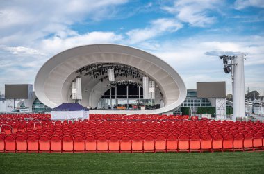 San Diego, California, ABD - 4 Ekim 2021: Jacobs Park 'taki White Rady Shell konser salonu. Kırmızı sandalyeler mavi bulutların altında yeşil çimlerin üzerinde.