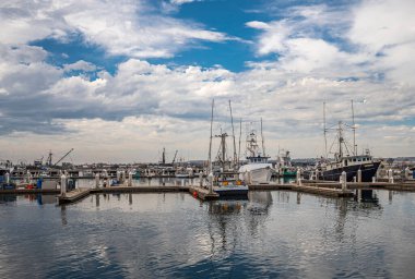 San Diego, California, ABD - 4 Ekim 2021 Embarcadero Tahta Yolu. Tuna Limanı 'na yanaşan balıkçı gemileri ağır bulutlu hava altında.