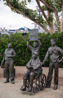 San Diego, California, ABD - 4 Ekim 2021: Bob Hope 'a Ulusal Selamlar ve 4 kişilik askeri heykel grubu, biri tekerlekli sandalyede, biri de içinde mesaj olan. Arkadaki yeşil yapraklar..