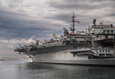 San Diego, California, ABD - 4 Ekim 2021: USS Midway Müzesi, Uçak Gemisi. Geminin iskele tarafı gri bulutlara karşı rıhtıma yanaştı..