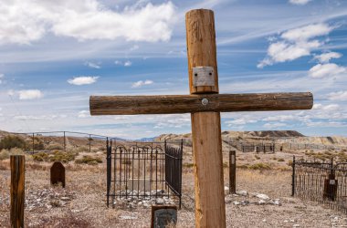 Tonopah, Nevada, ABD - 16 Mayıs 2011: Tarihi Mezarlık. Henry Hoppenburger 'in yakın çekimi, yanarak öldü, tahtadan haç gibi mavi bulutların altında kuru açık kahverengi çöl zemininde.
