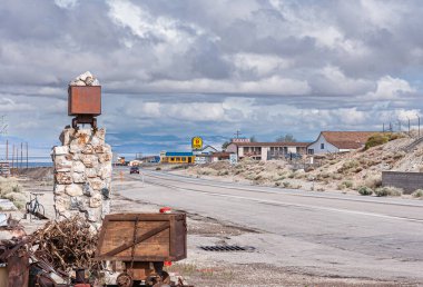 Tonopah, Nevada, ABD - 18 Mayıs 2011: Ağır gri bulutlar altında tarihi maden parkının önündeki kasaba manzarası. Motel binası ve maden vagonu önünde kaidesi olan yol..