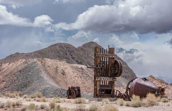 Тонопа, штат Невада, США - 18 мая 2011 года: Майнинг-парк. Коричневая деревянная башня лифта руины с отброшенными металлическими компонентами под голубым облаком и горы в задней части. 