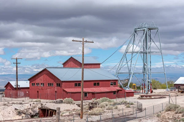 Tonopah Nevada 2011年5月18日 Historical Mining Park 灰色の雲の下の乾燥砂漠の床に設定された金属シャフトエレベータータワーと赤鉱山の建物と倉庫 — ストック写真